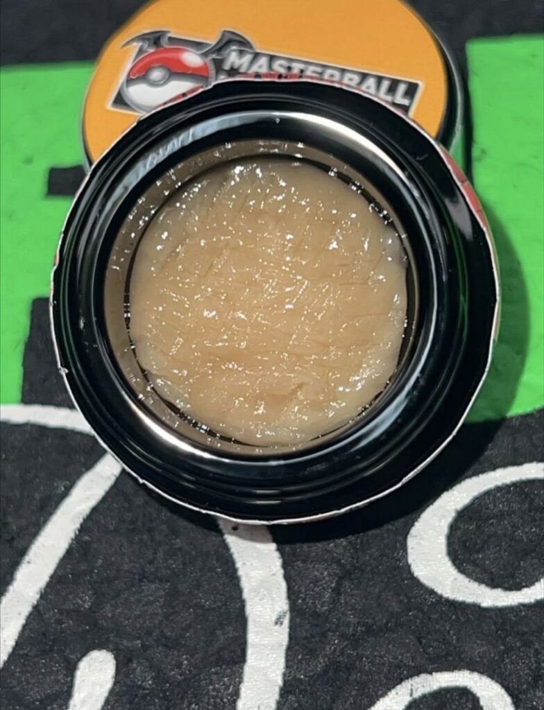 Strawboof THCa cold cure rosin with creamy golden texture in a clear jar, showcasing its glossy finish.